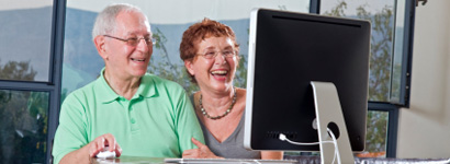Pareja de ancianos utilizando el ordenador y sonriendo